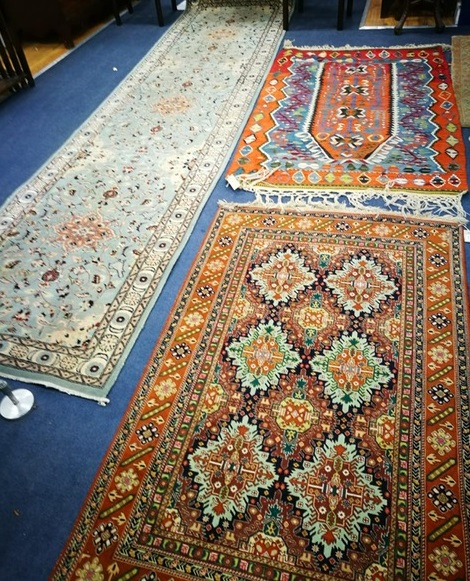 A Persian burnt orange ground rug, centred by six pale green lozenges and two other rugs